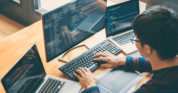 Professional male working in a tech environment, using three screens